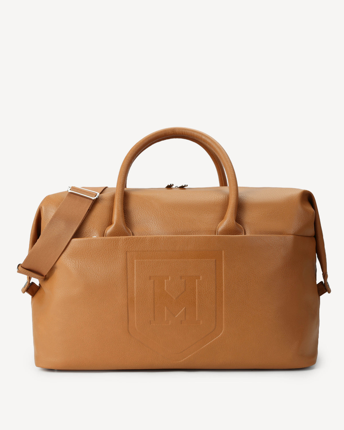 The Honorable Mention weekender in vegan leather with dual top handles, a detachable shoulder strap, and an embossed shield logo on the front, shown against a light grey background
