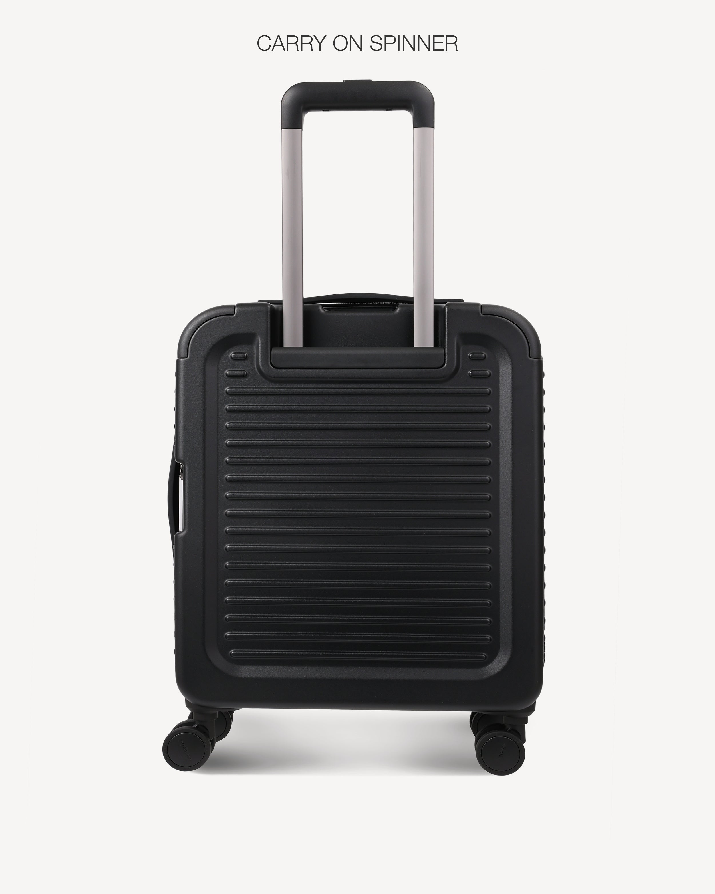 A black hard-shell spinner suitcase with a ribbed front panel and telescoping handle, shown on a light gray background with the text 'CARRY ON SPINNER' above it.