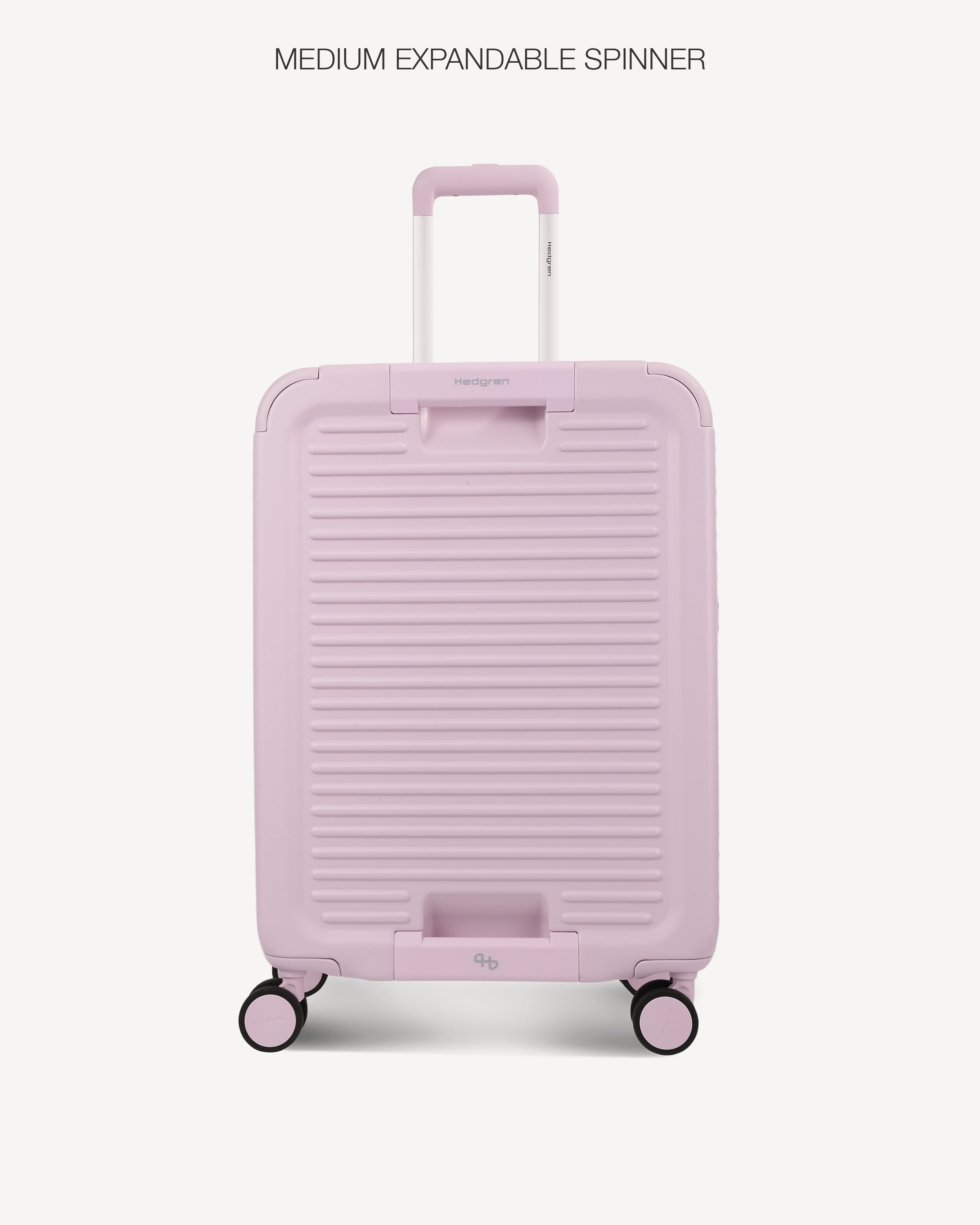 A light pink hardshell spinner suitcase with a ribbed front design, shown from the back against a light gray background. The text 'MEDIUM EXPANDABLE SPINNER' is printed at the top.