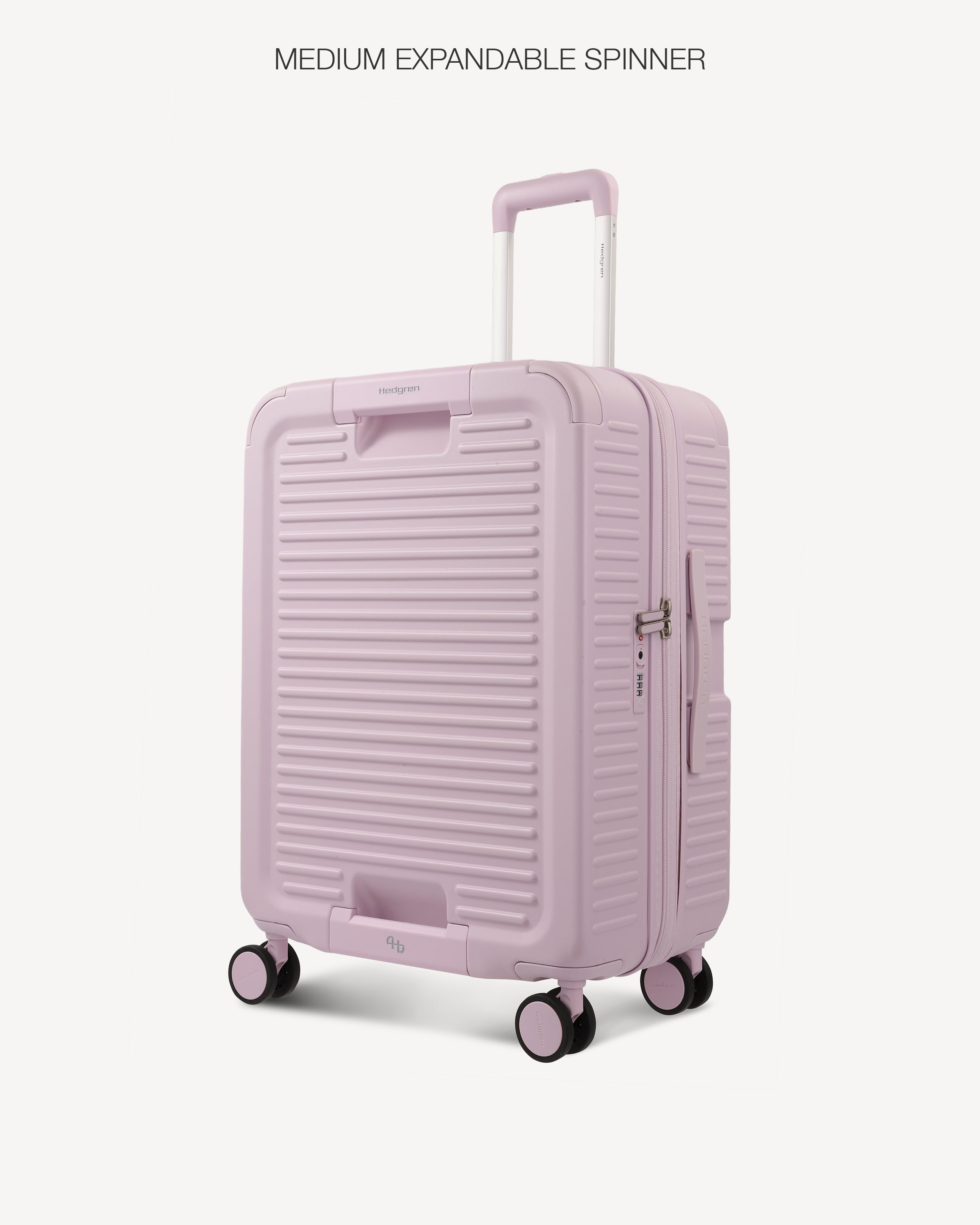 A light pink hardshell spinner suitcase with a ribbed front design, shown on a light gray background with the text 'MEDIUM EXPANDABLE SPINNER' at the top.