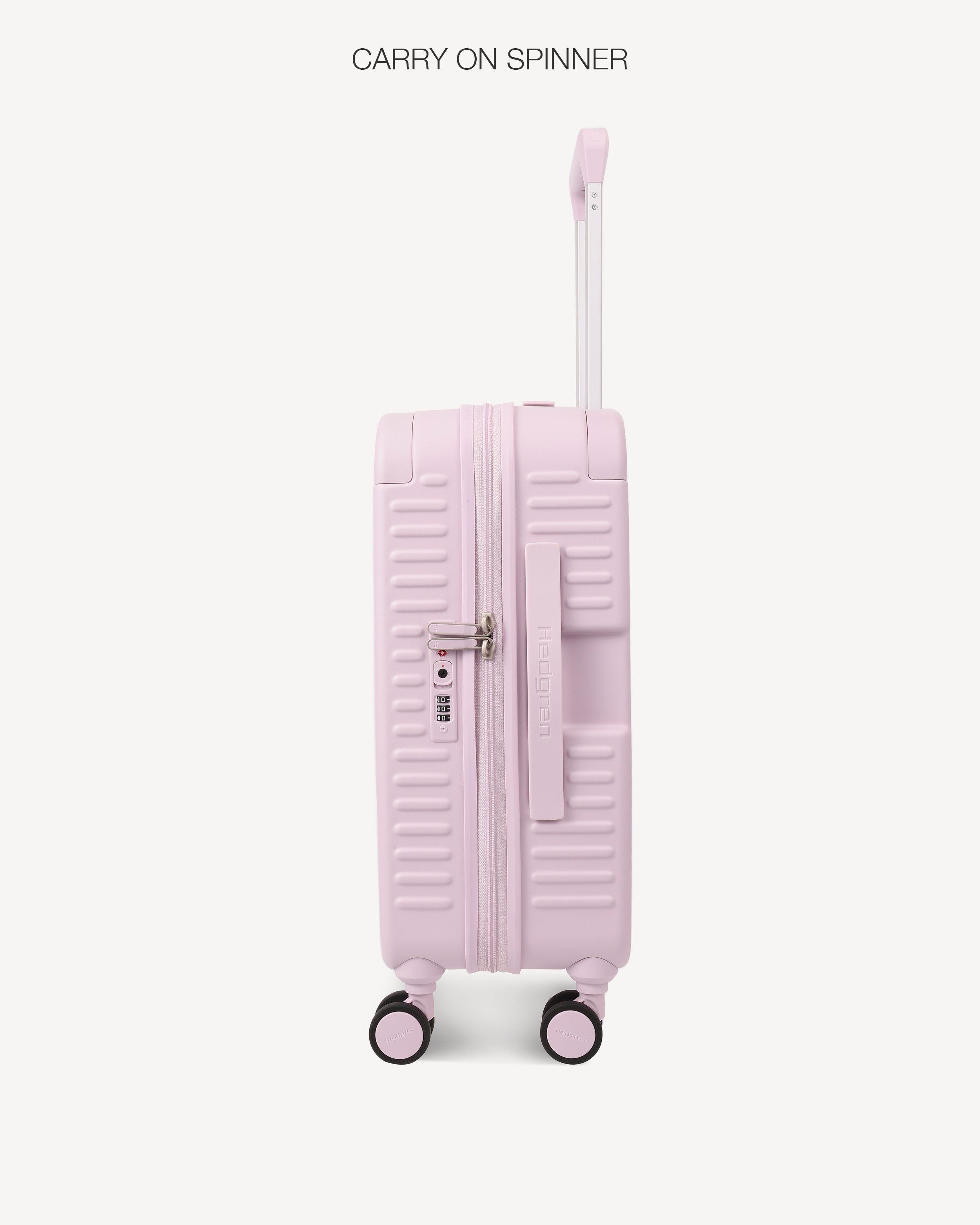 A light pink hard-shell carry-on spinner suitcase with an extended telescopic handle, shown from the back against a clean off-white background. The text 'CARRY ON SPINNER' is printed at the top.